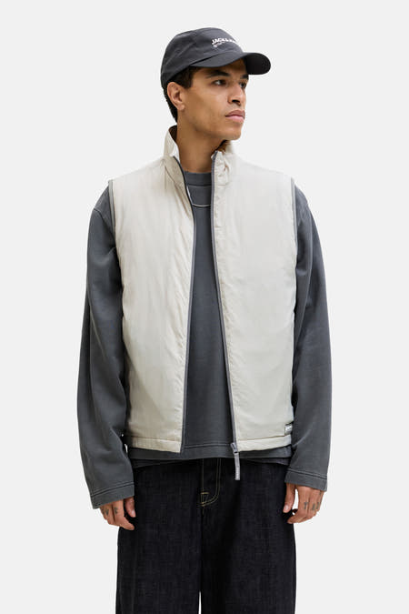 Grijze bodywarmer van CORE BY JACK & JONES, gecombineerd met een grijs sweatshirt en donkere denim broek.