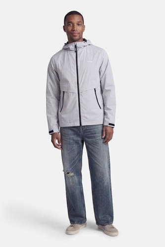 Veste courte grise de CORE BY JACK & JONES, avec capuche, poches zippées et portée avec un jean bleu et des baskets grises.