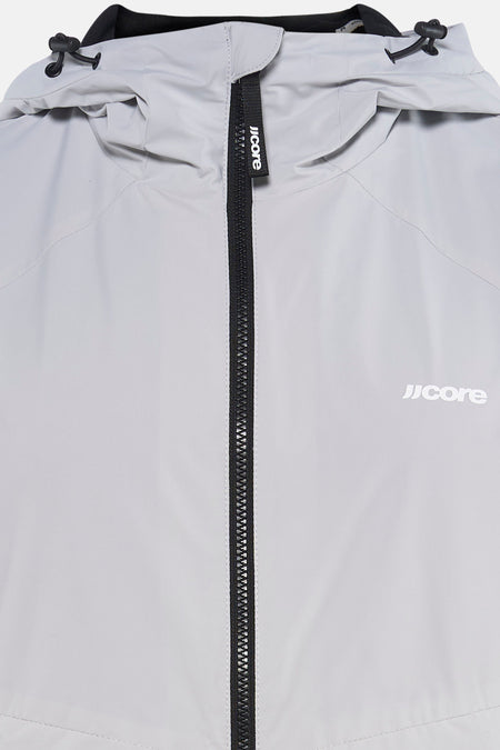 Grijs kort jasje van CORE BY JACK & JONES, met zwarte ritssluiting en logo op de voorkant, en trekkoorden aan de capuchon.
