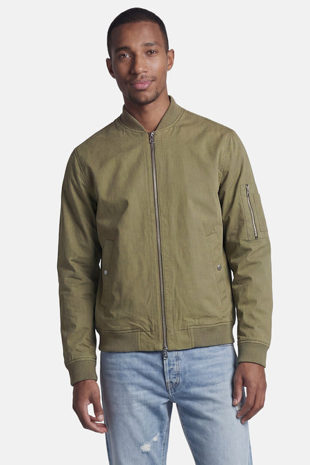 Veste courte verte de CORE BY JACK & JONES, style bomber avec fermeture éclair, poignets côtelés et poche sur la manche, portée par un homme.