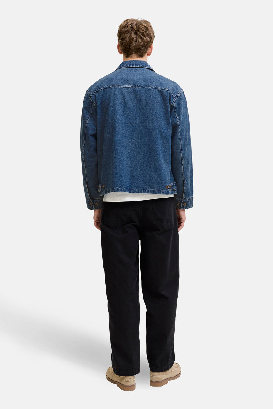 Jeansjas van mid blue denim van PREMIUM BLUE by JACK & JONES, gezien vanaf de achterkant, met zwarte broek en bruine schoenen.
