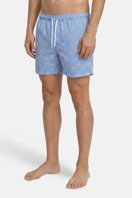 Blauwe zwemshort van JACK & JONES JEANS INTELLIGENCE met witte strepen, oranje ananassen, wit trekkoord en logo, gedragen door een man.