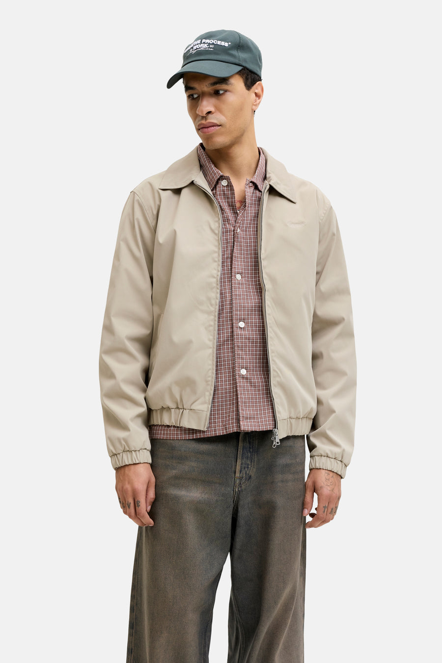 Manteau court beige de ORIGINALS BY JACK & JONES, avec une chemise à carreaux et un jean foncé.