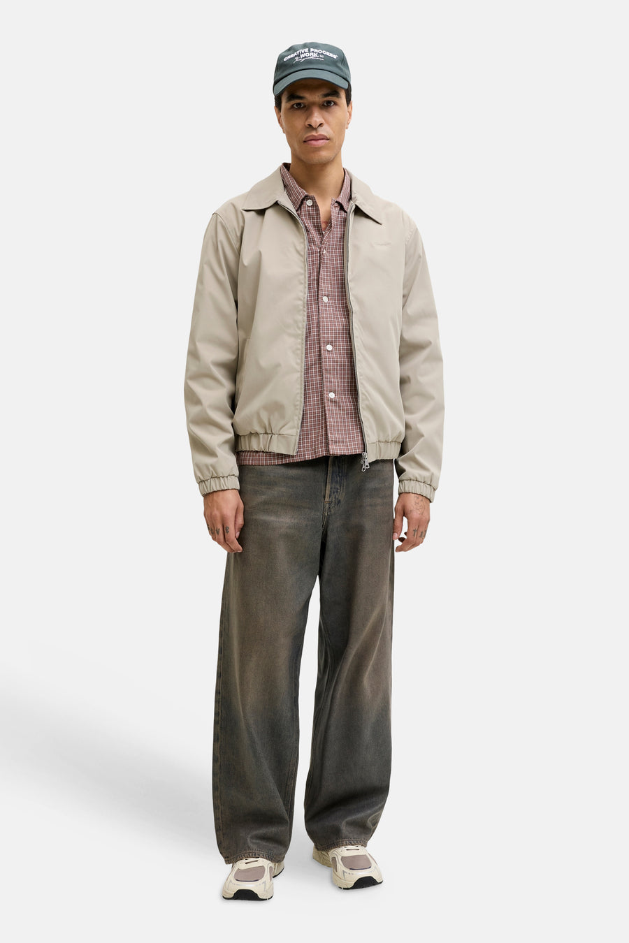 Manteau court beige de ORIGINALS BY JACK & JONES, avec une chemise à carreaux, un jean ample et une casquette.