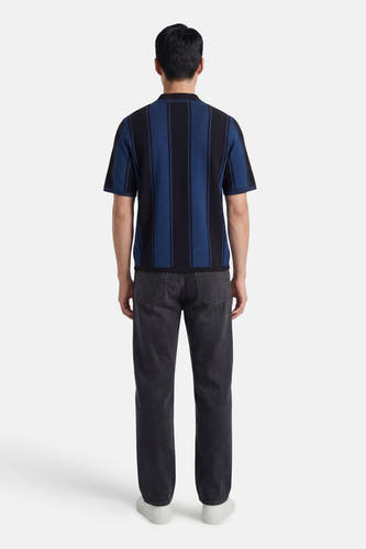 Veelkleurige polo met korte mouwen van CORE BY JACK & JONES, met verticale strepen aan de achterkant, gecombineerd met grijze jeans en witte sneakers.