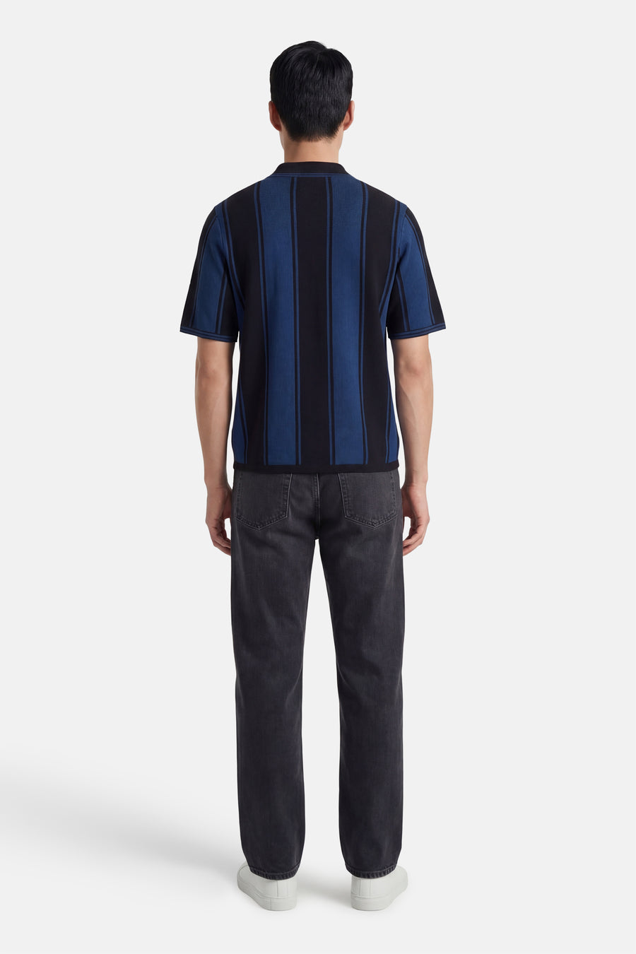 Veelkleurige polo met korte mouwen van CORE BY JACK & JONES, met verticale strepen aan de achterkant, gecombineerd met grijze jeans en witte sneakers.