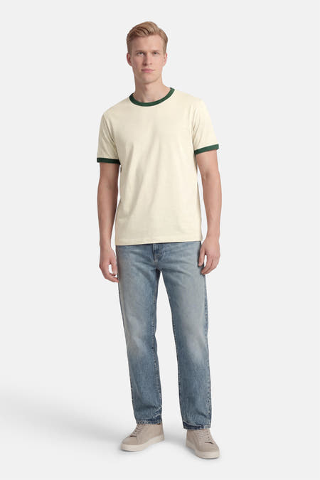 Beige T-shirt met korte mouwen van ORIGINALS BY JACK & JONES, met een groene rand bij de hals en mouwen, gedragen met jeans en sneakers.
