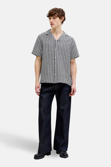 Blauw overhemd met korte mouwen van ORIGINALS BY JACK & JONES, voorzien van een all-over grafisch patroon en gedragen met wijde donkere jeans.