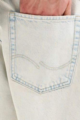 Lichtblauwe denim short van JACK & JONES JEANS INTELLIGENCE met een hand in de achterzak en gele stiksels.