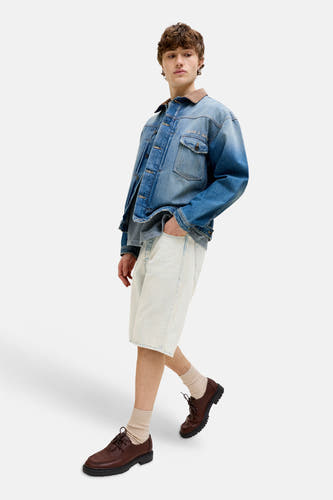 Lichtblauwe denim short tot de knieën van JACK & JONES JEANS INTELLIGENCE, gedragen met een spijkerjack en bruine schoenen.
