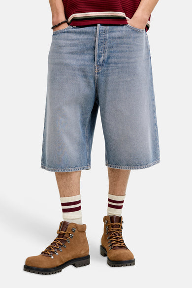 Middenblauw denim short van JACK & JONES JEANS INTELLIGENCE, met een losse pasvorm en gecombineerd met gestreepte sokken en bruine veterlaarzen.