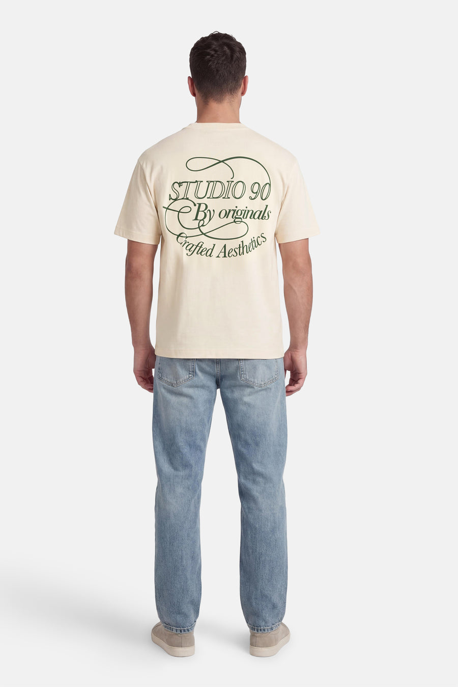 Ecru T-shirt met korte mouwen van Originals by Jack & Jones, met groene tekst op de rug en jeans.