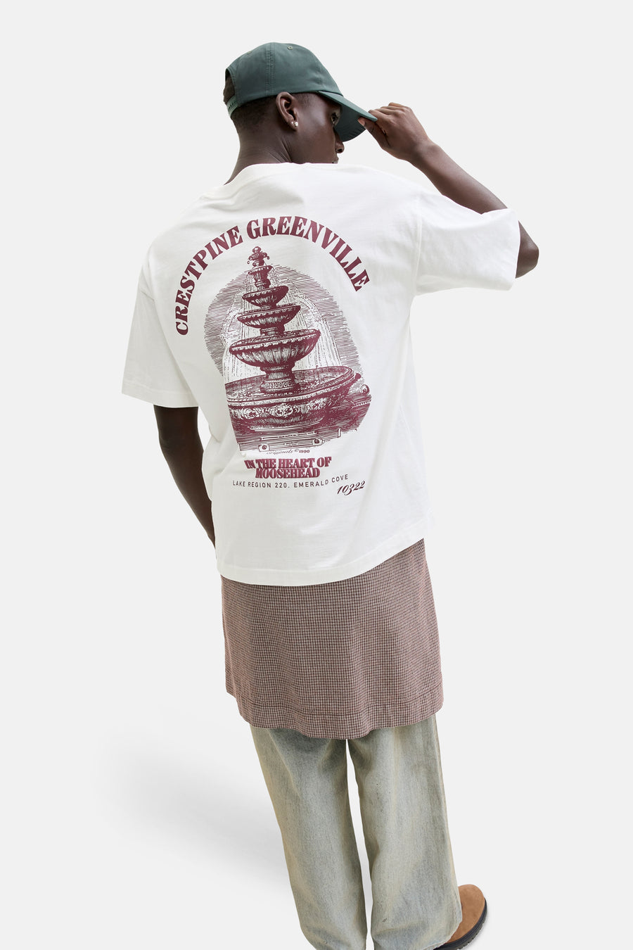 Wit T-shirt van ORIGINALS BY JACK & JONES, met grafische print op de rug en gecombineerd met een geruite rok en wijde jeans.
