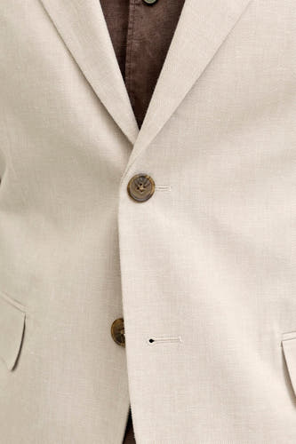 Detail van een ecru blazer van PREMIUM by JACK & JONES van structuurstof, met bruine knopen en een bruin overhemd eronder.