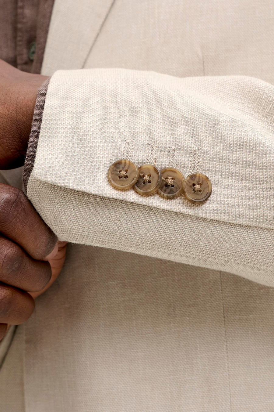 Ecru blazer van PREMIUM by JACK & JONES met een herringbone weefsel, detail van de mouw met vier bruine knopen.