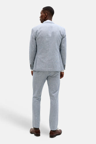 Blauwe blazer van PREMIUM by JACK & JONES met textuur, van achteren gezien, gedragen over een witte blouse met bijpassende pantalon en bruine schoenen.