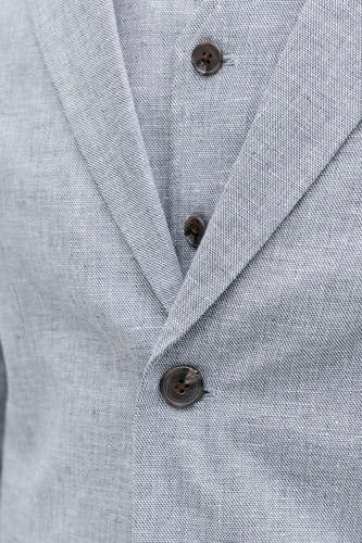 Blauwe blazer van PREMIUM by JACK & JONES met subtiele weeftextuur en drie bruine knopen, detailopname.