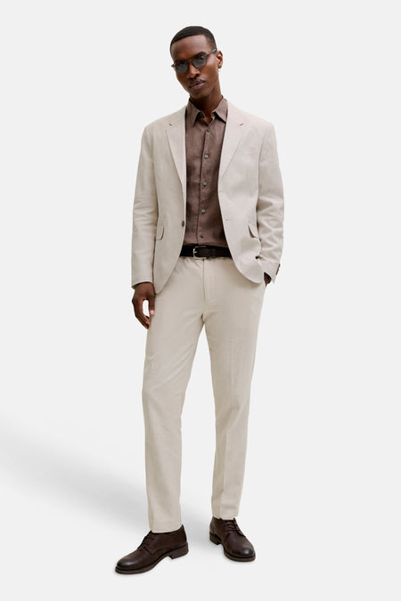 Ecru kostuumbroek van PREMIUM by JACK & JONES, gecombineerd met een bruin overhemd, zwarte riem en bruine leren schoenen.