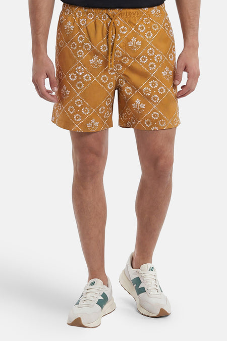 Gele zwemshort van PREMIUM by JACK & JONES met wit bloemen- en ruitpatroon en trekkoord, gedragen door een man.