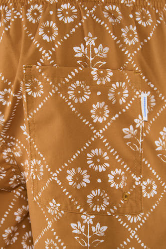 Gele zwemshort van PREMIUM by JACK & JONES met wit bloemen- en stippenpatroon, inclusief een achterzak met merklabel en gouden stiksels.