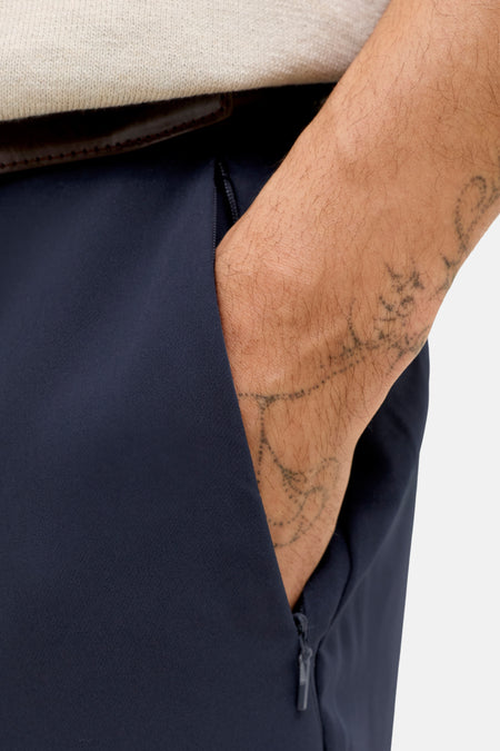 Blauwe kostuumbroek van PREMIUM by JACK & JONES, met bruine riem en een hand in de zak.