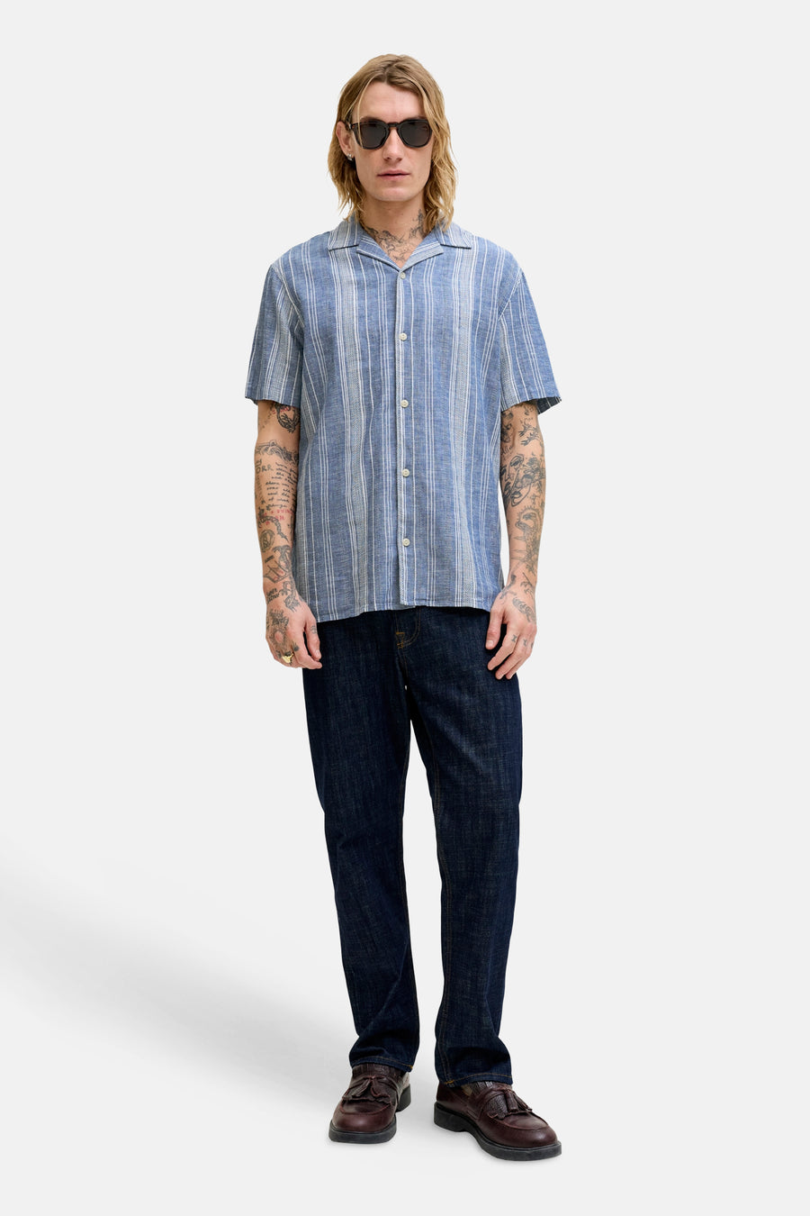 Blauw gestreept overhemd met korte mouwen van PREMIUM BLUE by JACK & JONES, met tattoos op de armen en een zonnebril.