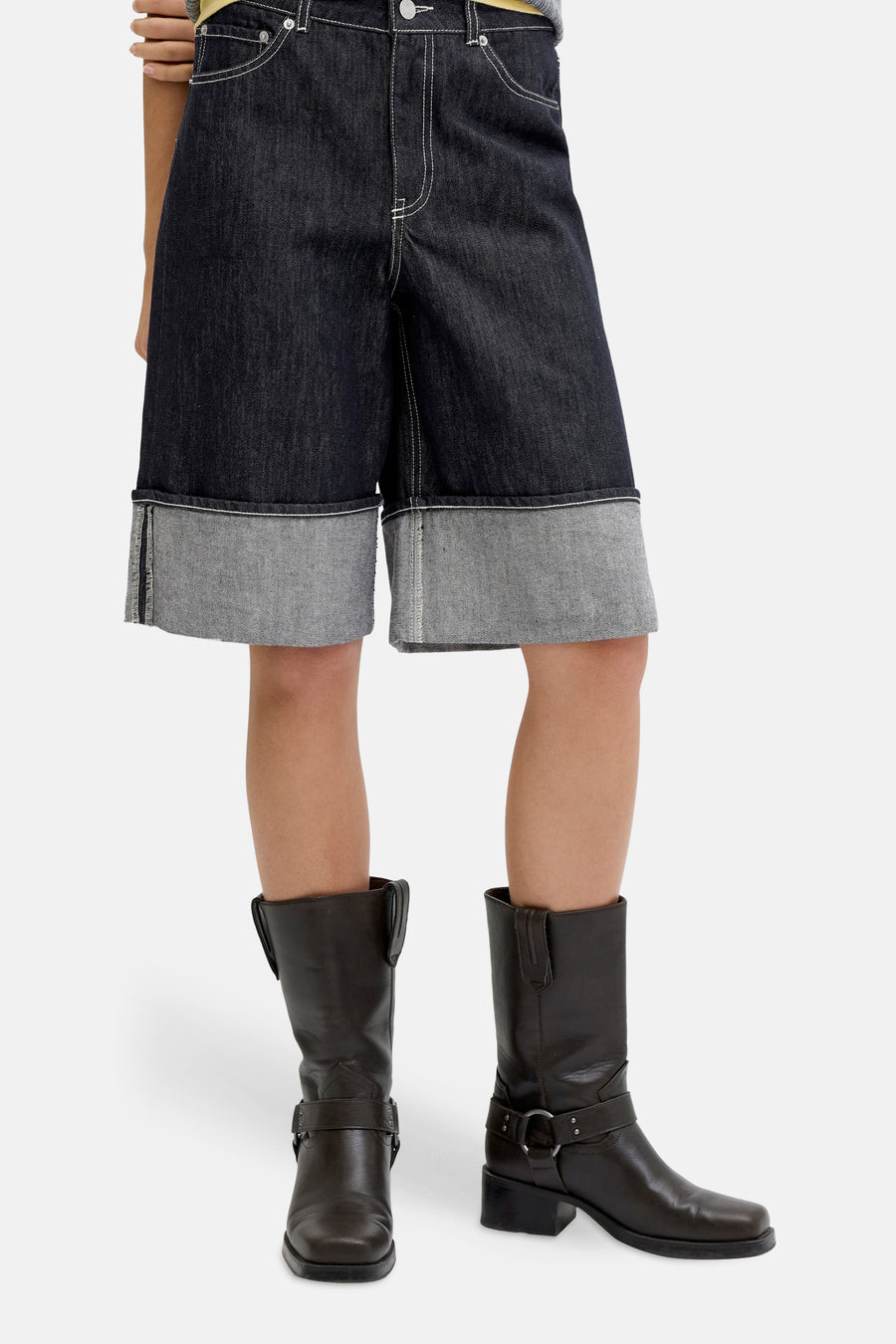Donkerblauwe denim short van JJXX, met opgerolde zoom en witte stiksels, gecombineerd met leren laarzen.