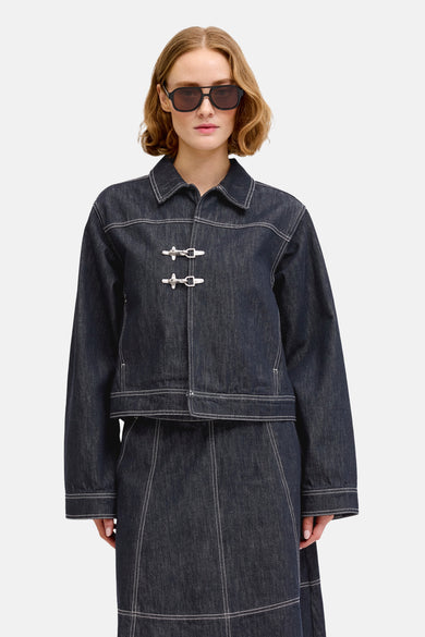 Donkerblauwe denim jeansjas van JJXX, met witte stiksels en zilverkleurige knevelsluitingen.