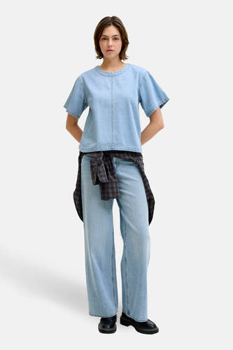 Lichtblauwe denim blouse met korte mouwen van JJXX, met een nonchalante geknoopte blouse om de taille en wijde jeans.
