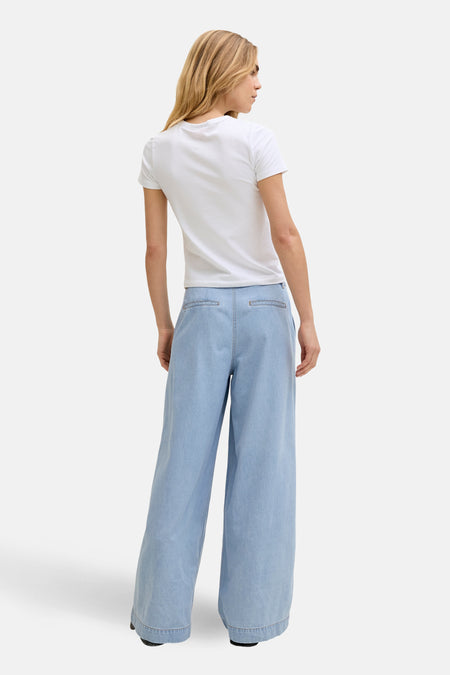 Lichtblauwe denim jeans wide van JJXX, met wijde pijpen, gezien van achteren met een wit T-shirt.
