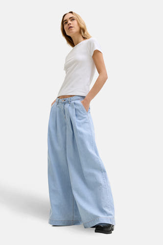 Lichtblauwe denim jeans wide van JJXX, met plooien en wijde pijpen, gecombineerd met een wit T-shirt.
