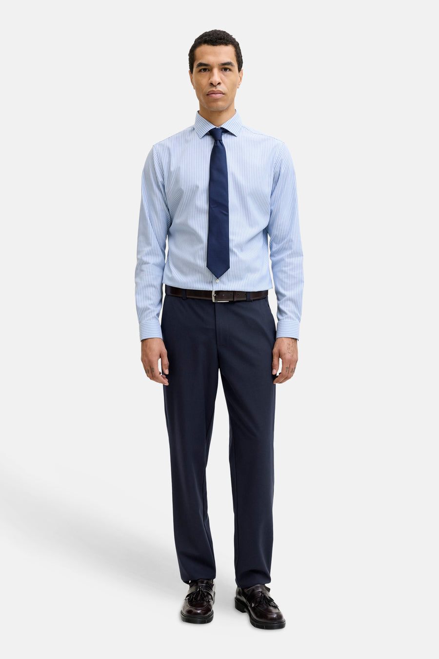 Blauwe broek van JACK & JONES JEANS INTELLIGENCE, gecombineerd met een gestreept overhemd, een stropdas en leren schoenen.