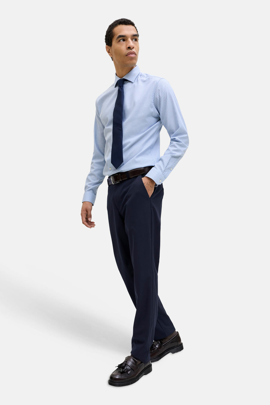 Pantalon bleu de JACK & JONES JEANS INTELLIGENCE, combiné avec une chemise rayée, une cravate et des mocassins en cuir.