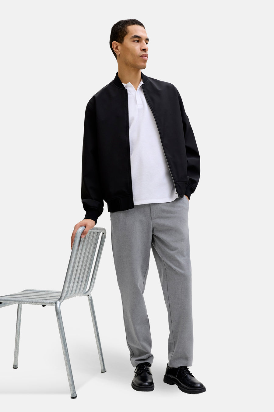 Pantalon gris de JACK & JONES JEANS INTELLIGENCE, combiné avec un polo blanc et un blouson bomber noir.
