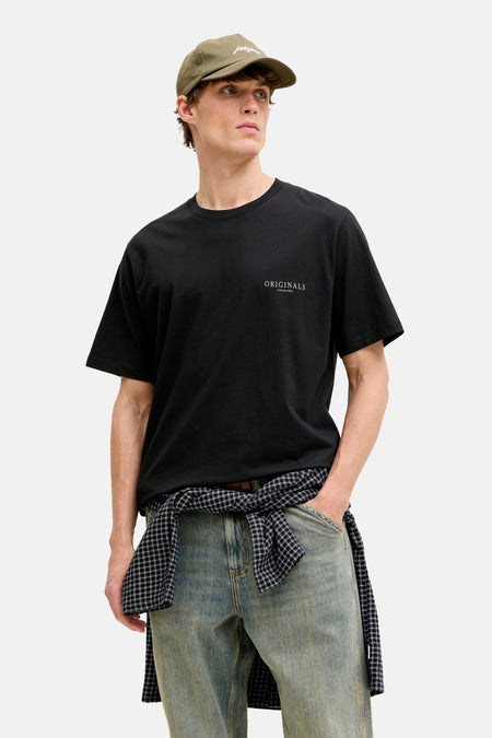 T-shirt noir de ORIGINALS BY JACK & JONES, avec une chemise nouée à la taille et une casquette sur la tête.