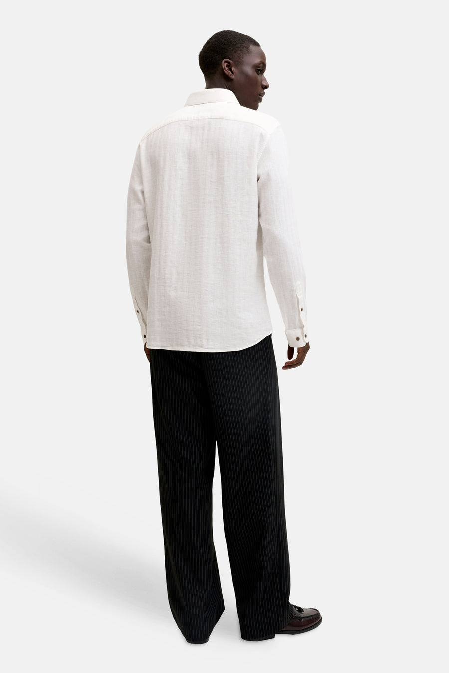 Wit, gestructureerd overhemd met lange mouwen van PREMIUM by JACK & JONES, gezien vanaf de achterkant, gedragen met een zwarte pinstripe broek en donkerbruine loafers.