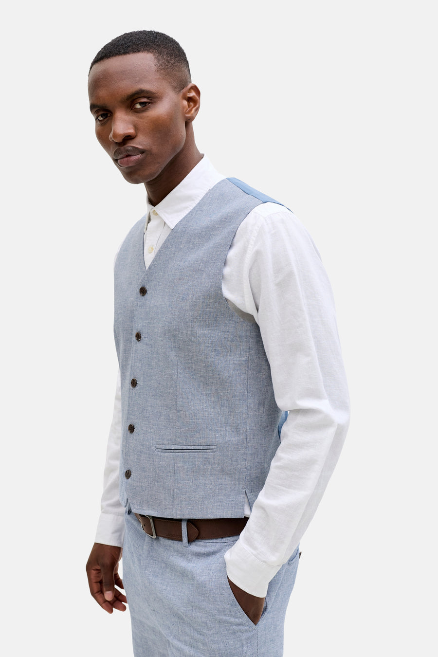Gilet bleu de PREMIUM by JACK & JONES, avec fermeture boutonnée et une subtile poche poitrine, porté sur une chemise blanche.