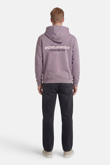 Paarse sweater met kap van CORE BY JACK & JONES, met tekstprint op de achterkant, gecombineerd met een zwarte jeans en suède schoenen.
