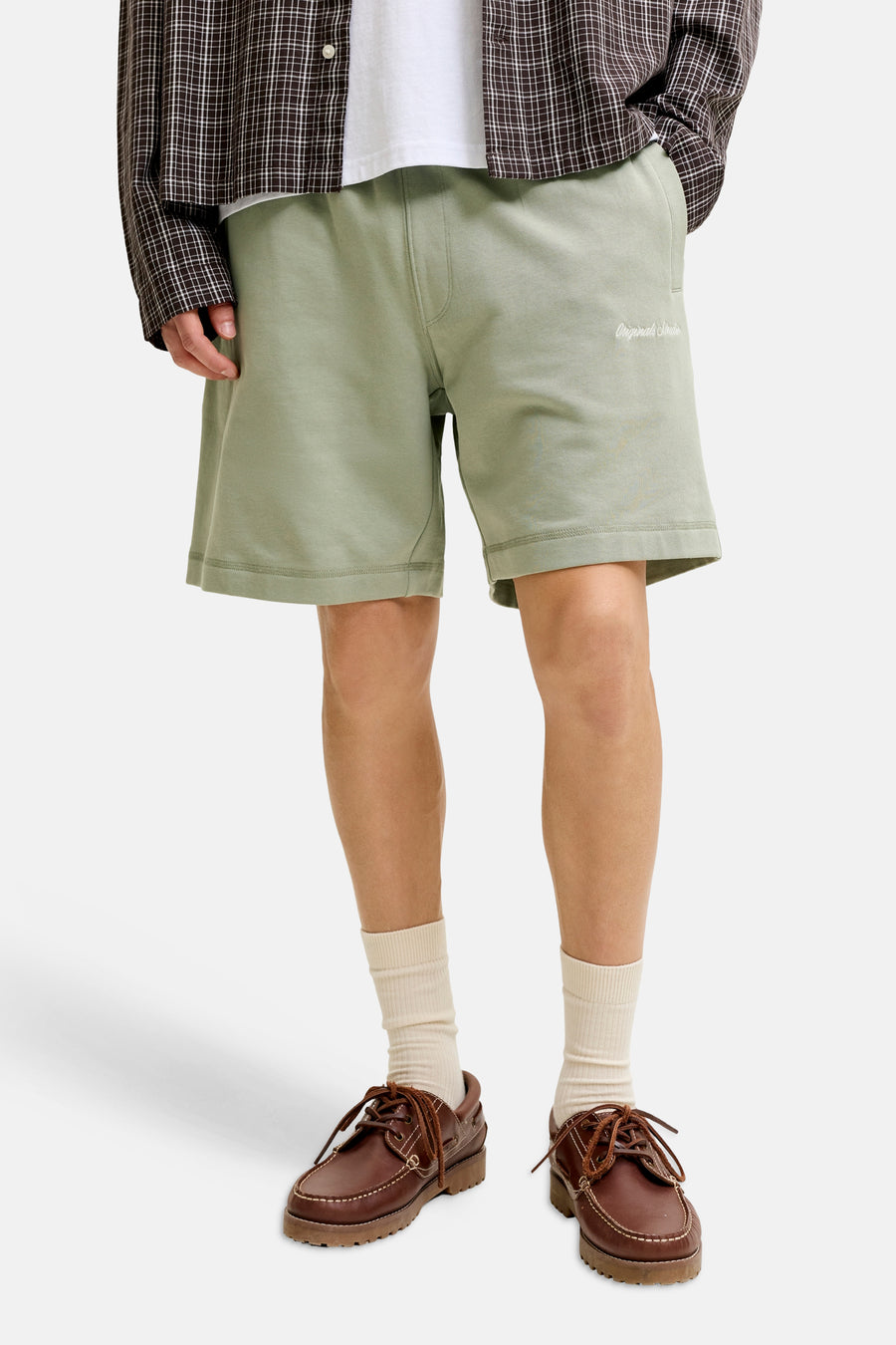 Short vert de JACK & JONES JEANS INTELLIGENCE avec logo brodé, porté avec une chemise à carreaux et des mocassins marron.