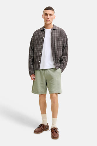 Short vert de JACK & JONES JEANS INTELLIGENCE avec logo brodé, porté par un homme avec une chemise à carreaux et un T-shirt blanc.