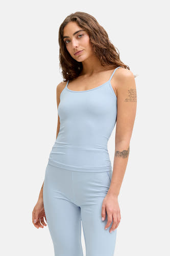 Blauwe top met spaghettibandjes van JJXX, met mouwtatoeages en bijpassende blauwe broek.