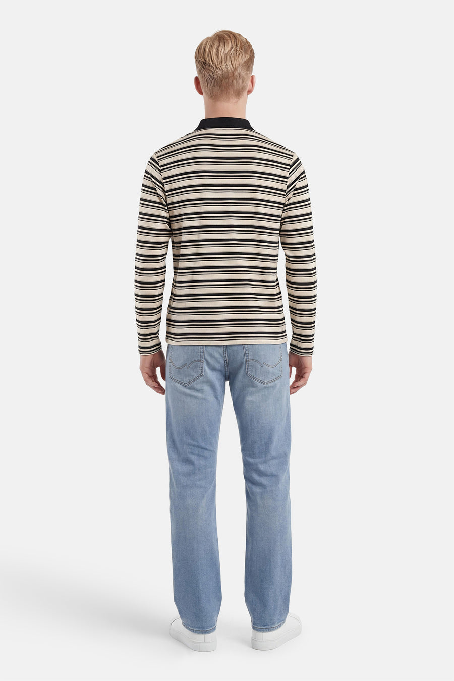 Polo multicolore à manches longues d'ORIGINALS BY JACK & JONES, avec des rayures horizontales crème et noires et un col polo noir, vue de dos sur un homme en jean et baskets blanches.
