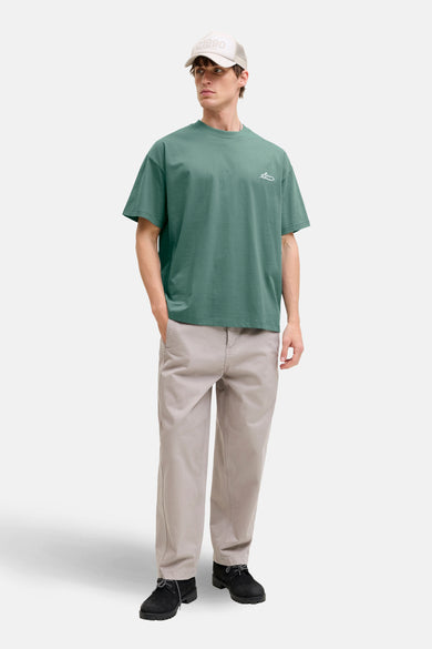 Groen T-shirt met korte mouwen van CORE BY JACK & JONES, met een kleine print, gecombineerd met kaki broek en een pet.
