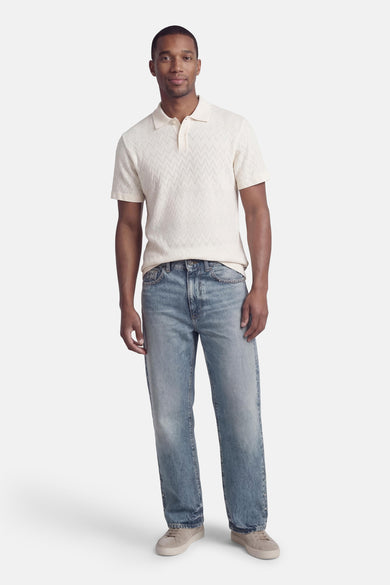 Ecru polo van PREMIUM by JACK & JONES met een subtiel zigzagpatroon, gedragen met blauwe jeans en suède sneakers.
