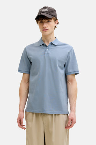 Blauwe polo van PREMIUM BLUE by JACK & JONES, gedragen met een pet en khaki broek.
