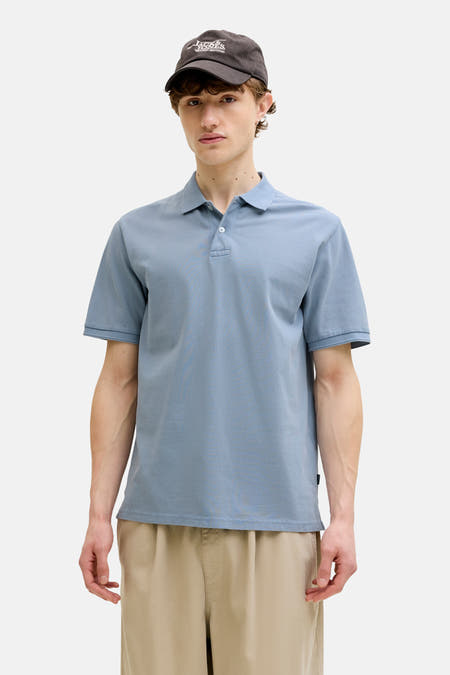 Polo bleu de PREMIUM BLUE by JACK & JONES, porté avec une veste marron et un pantalon beige.