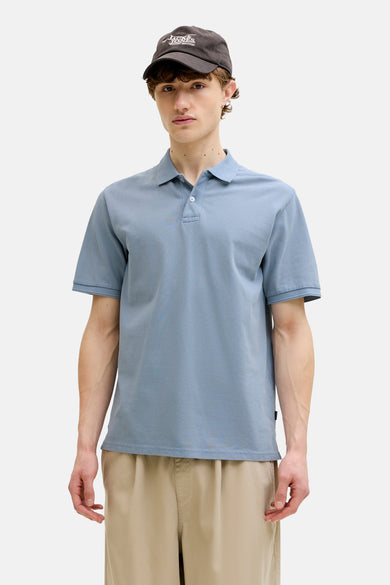 Blauwe polo van PREMIUM BLUE by JACK & JONES, gedragen met een pet en khaki broek.
