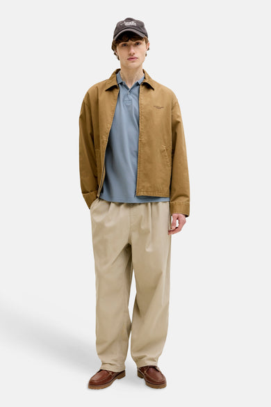 Blauw poloshirt van PREMIUM BLUE by JACK & JONES, gedragen met een bruine jas en beige broek.