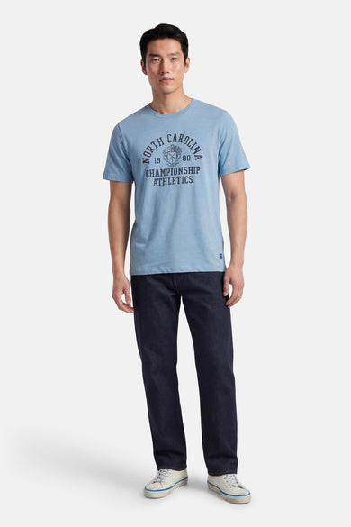 Blauw T-shirt van PREMIUM BLUE by JACK & JONES, met een "North Carolina" print en donkere jeans met witte sneakers.