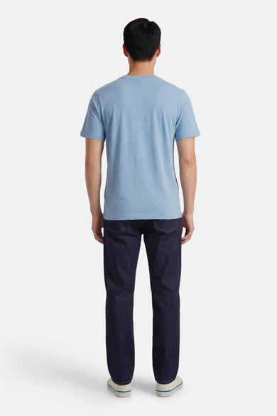 Blauw T-shirt van PREMIUM BLUE by JACK & JONES, achterkant gezien, met donkere jeans en witte schoenen.